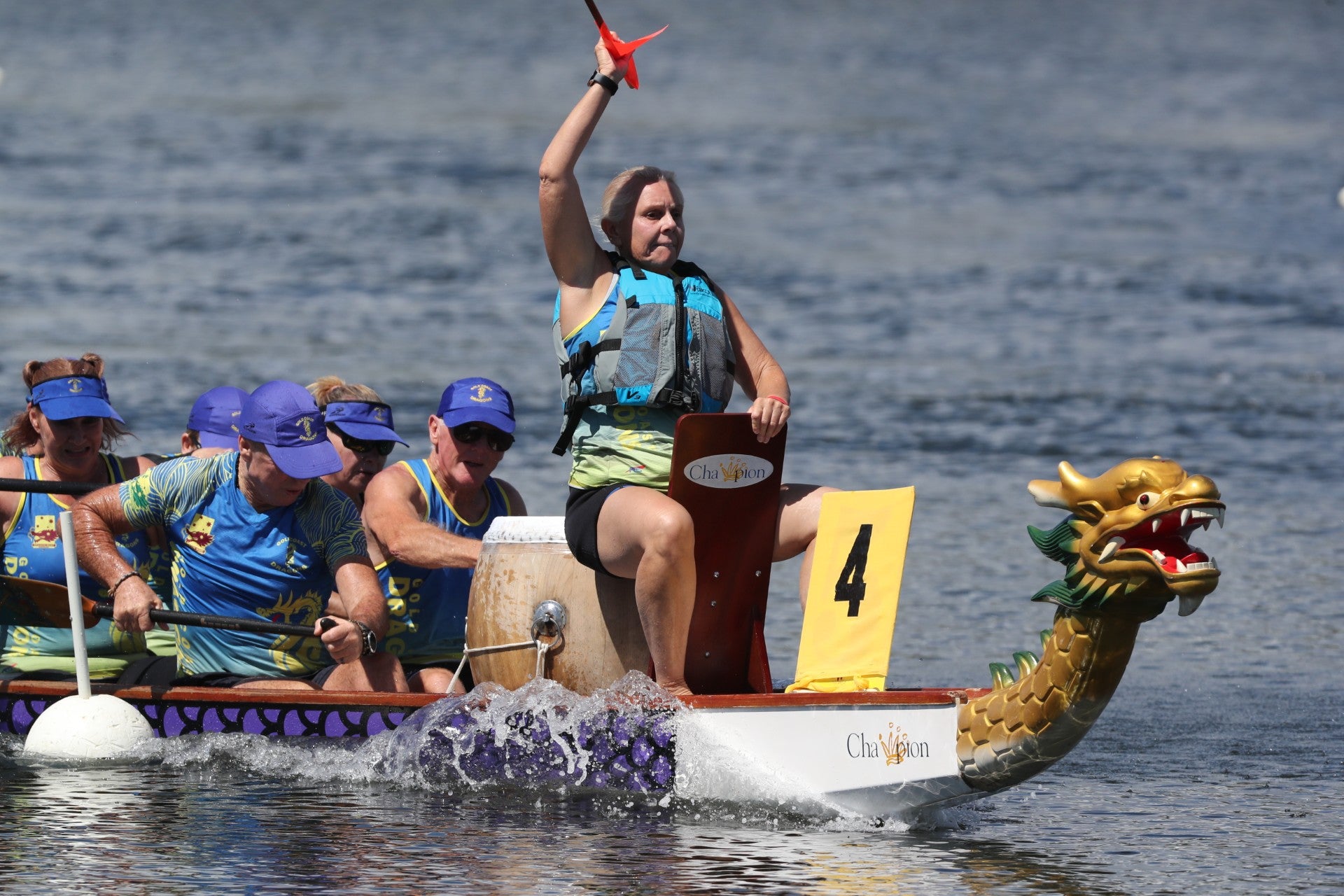 A dragon boat drummer with hand up in the air ready to strike the drum. 
