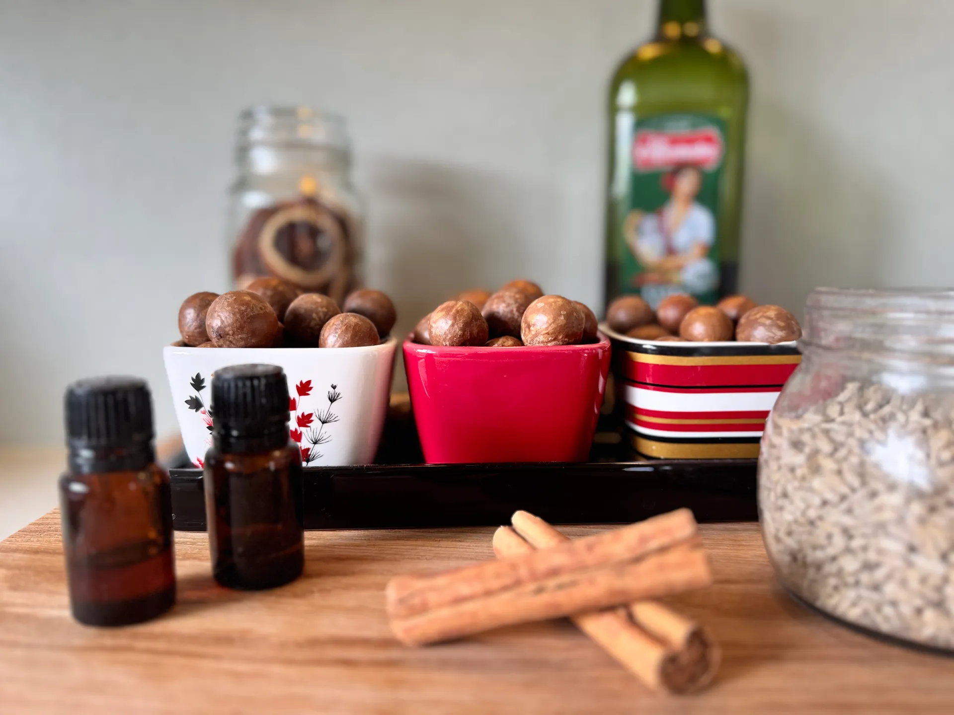 essential oils, cinamon stick, macadamias, sesame seeds, olive oil and dried oranges on a board