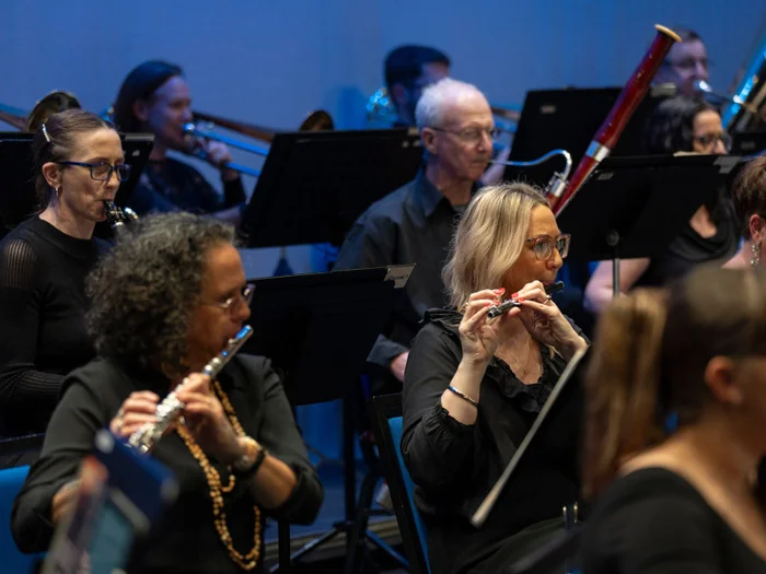 Sunshine Coast Symphony Orchestra. Summer Serenades concert. Two women playing flutes with other members of the orchestra sat behind them playing other musical instruments. 