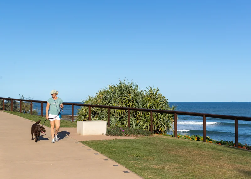 Woman walking medium sized dog on-leash along Coastal Pathway