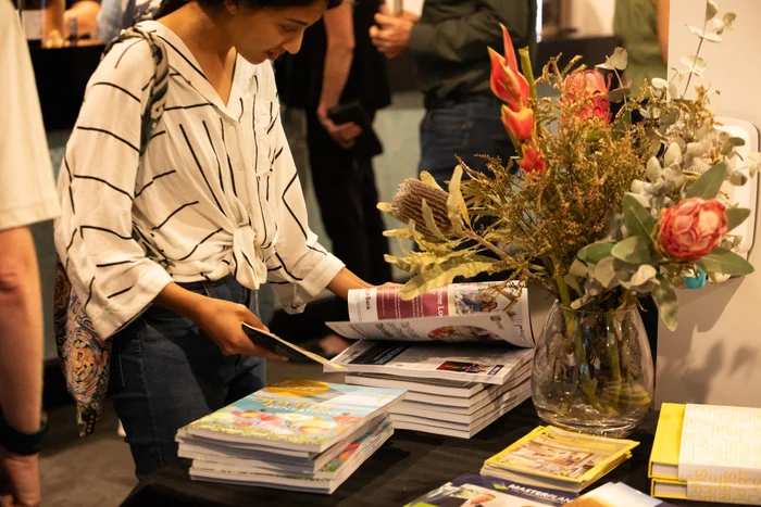 Attendee reading Open House book at Coolum Civic event. 