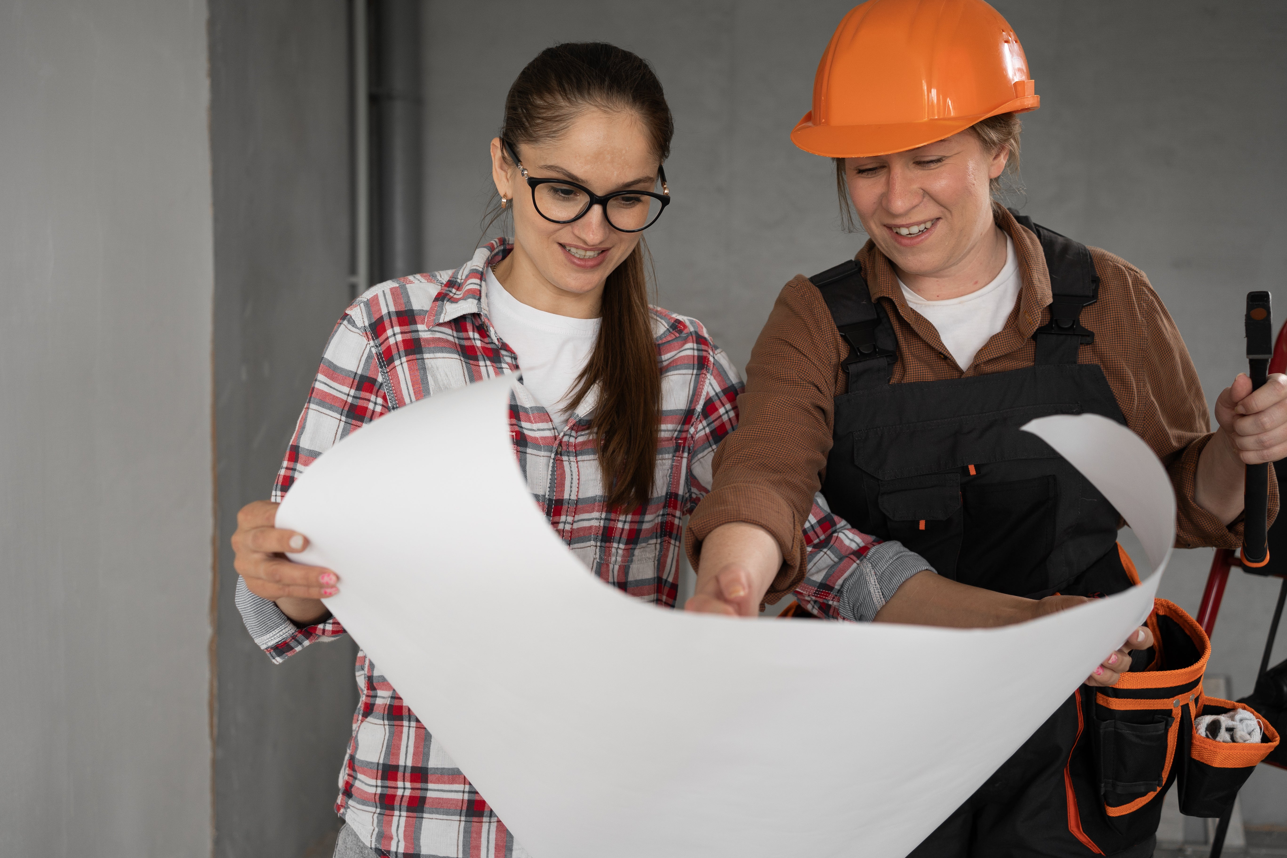 two women, one in a hard hat looking at building plans