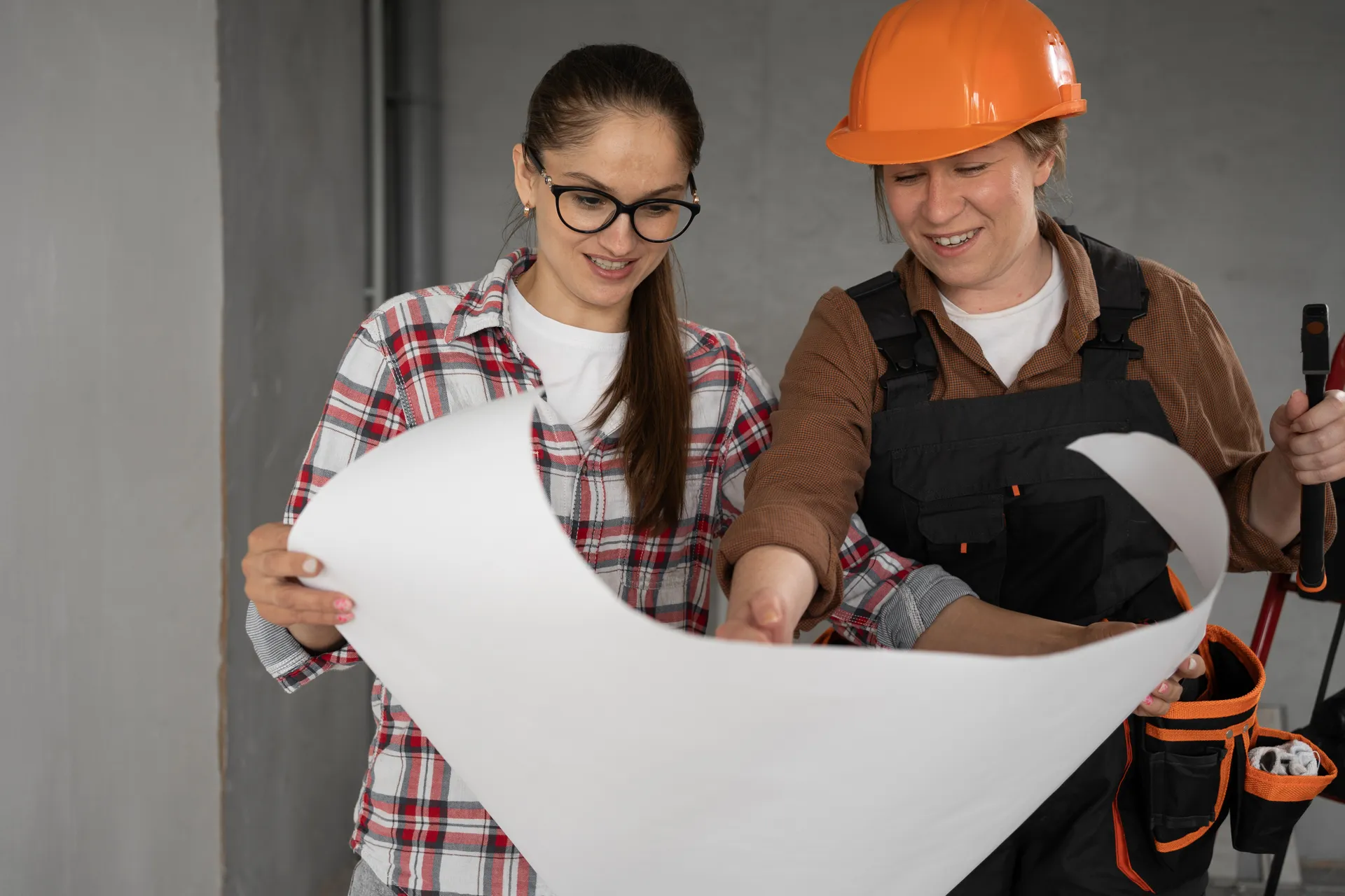 two women, one in a hard hat looking at building plans