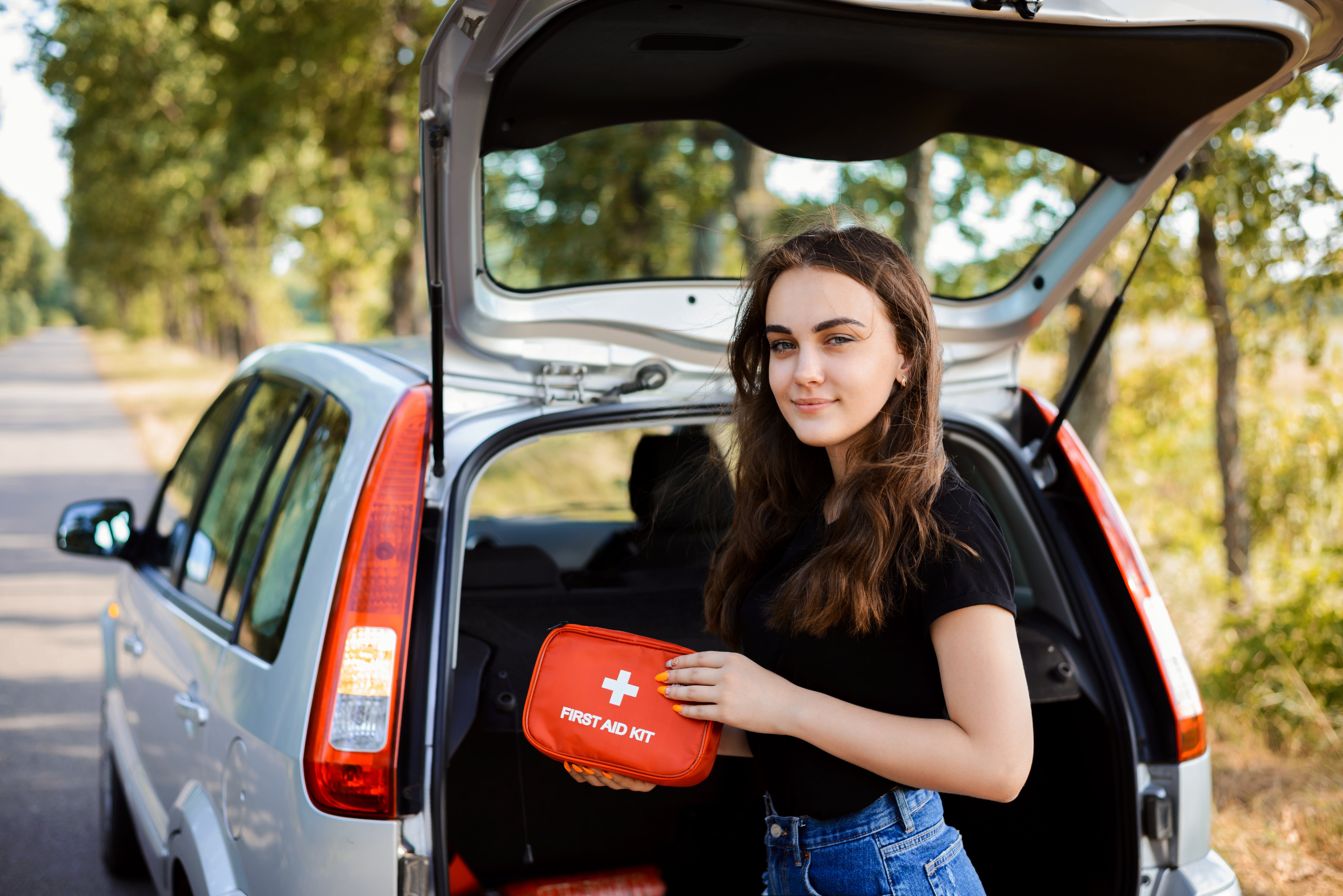 woman standing at the back of her car with a first aid kit