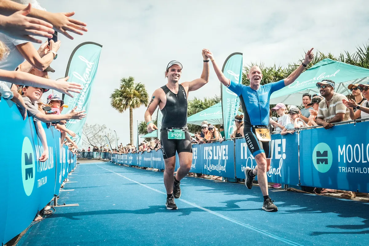 Two runners holding hands to cross the finish line