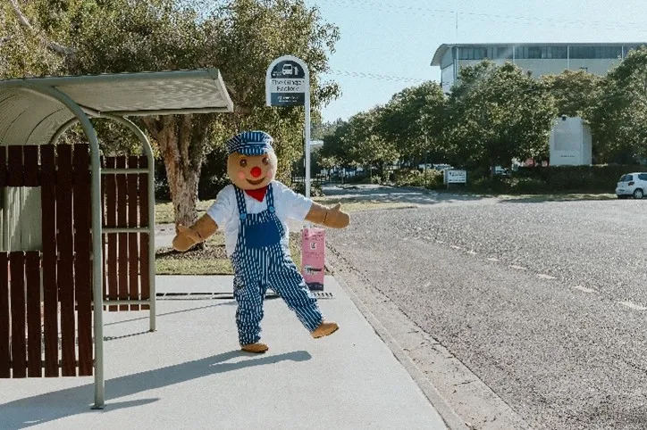 Gingerbread man standing in front of bus stop.