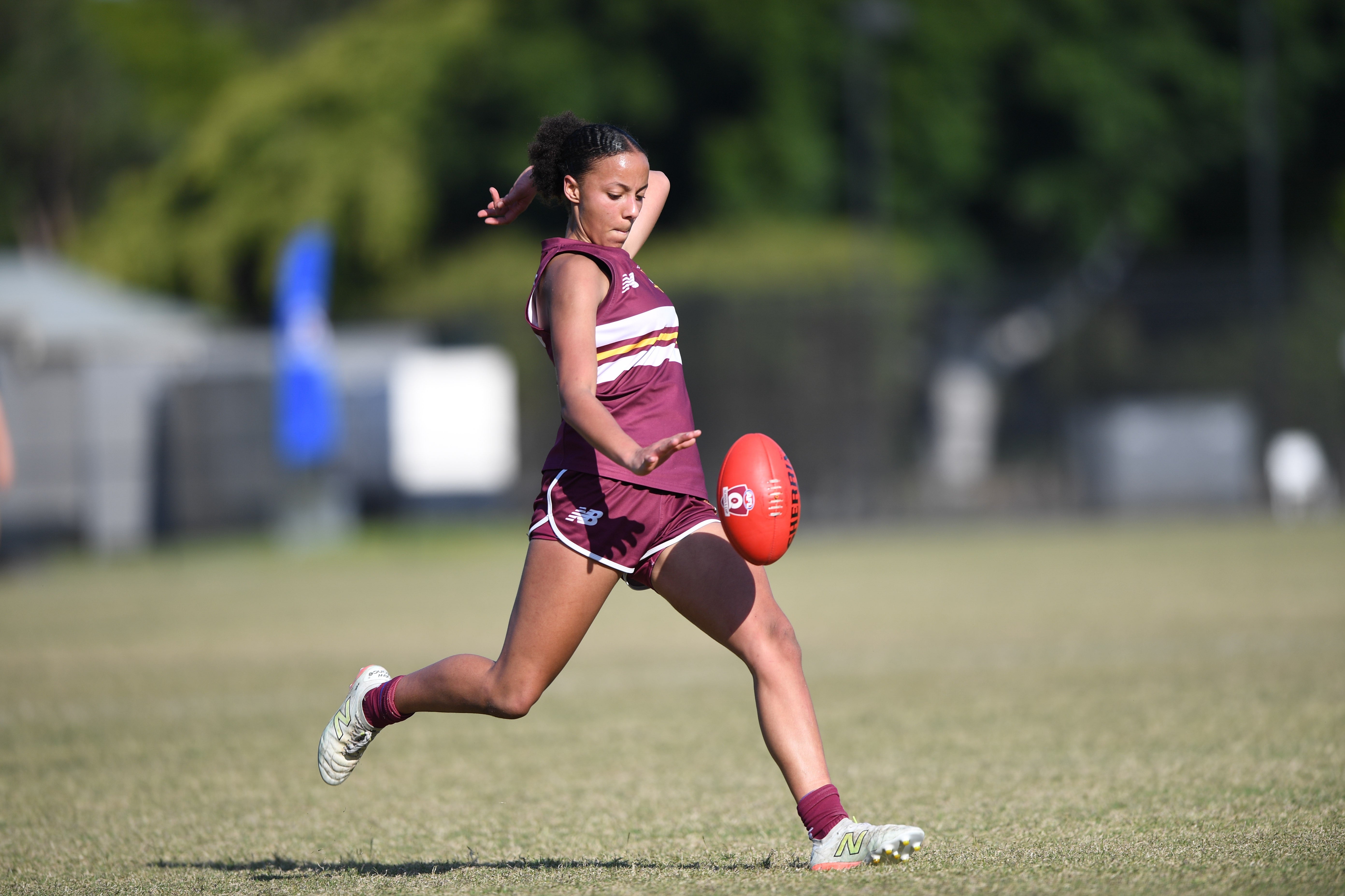 Student in a running motion - just let go of the ball and about to kick.