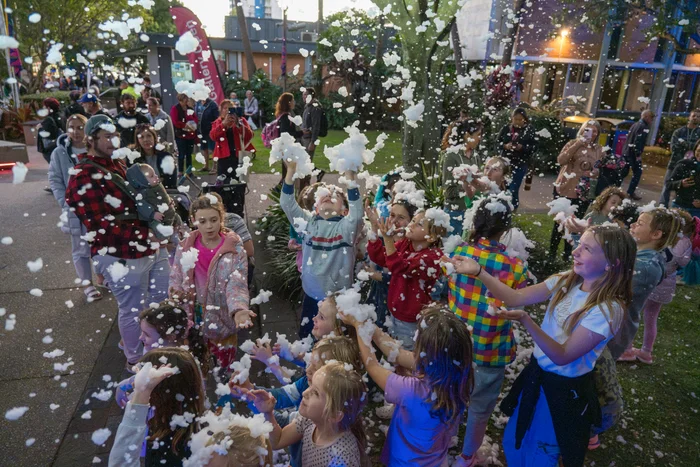 Children playing and reaching out to touch snow (artificial snow).