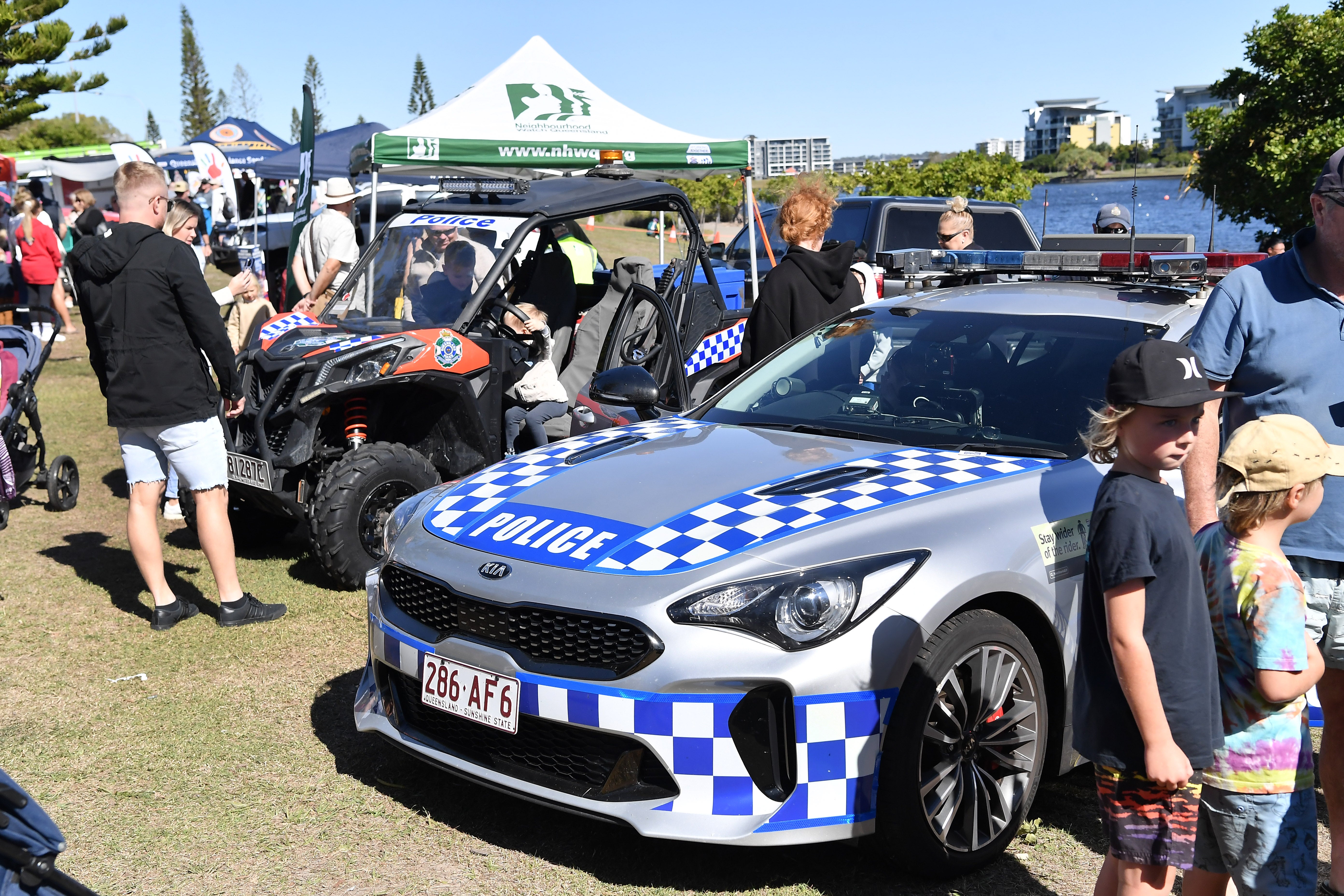 Groups of young families inspect a police car and ATV vehicle.