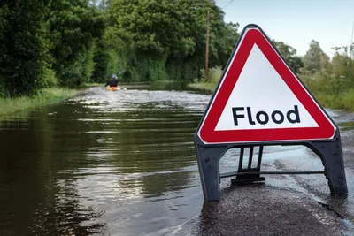 A flooded road with someone kayaking through the water
