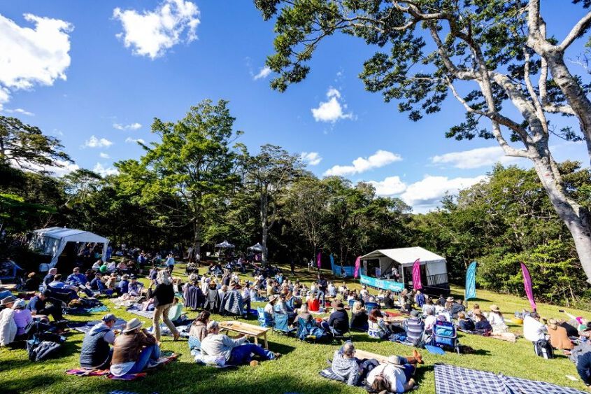 A sweeping view of the hill filled with people on picnic blankets looking towards a stage 