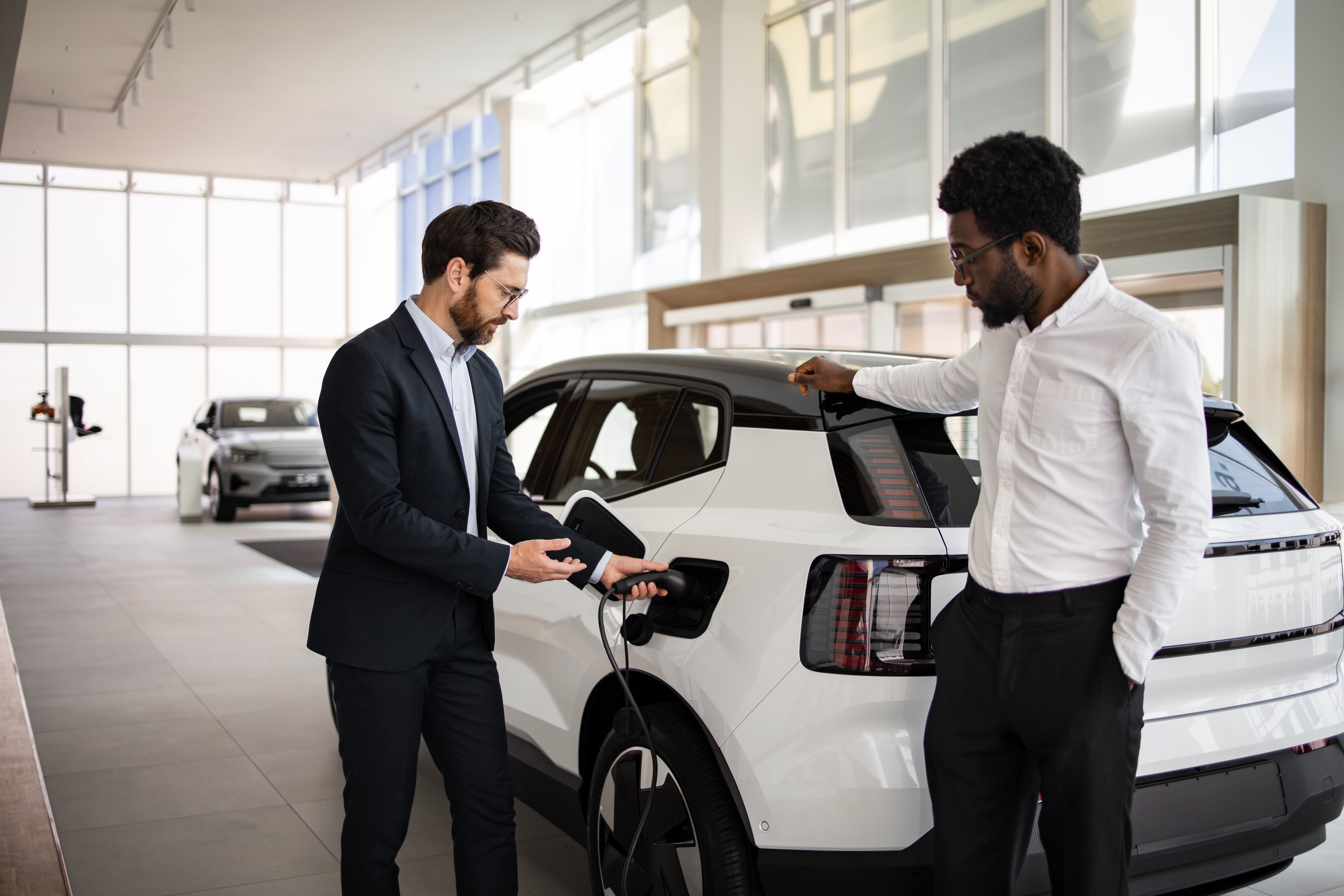 EV showroom, salesman demonstrates charging an EV