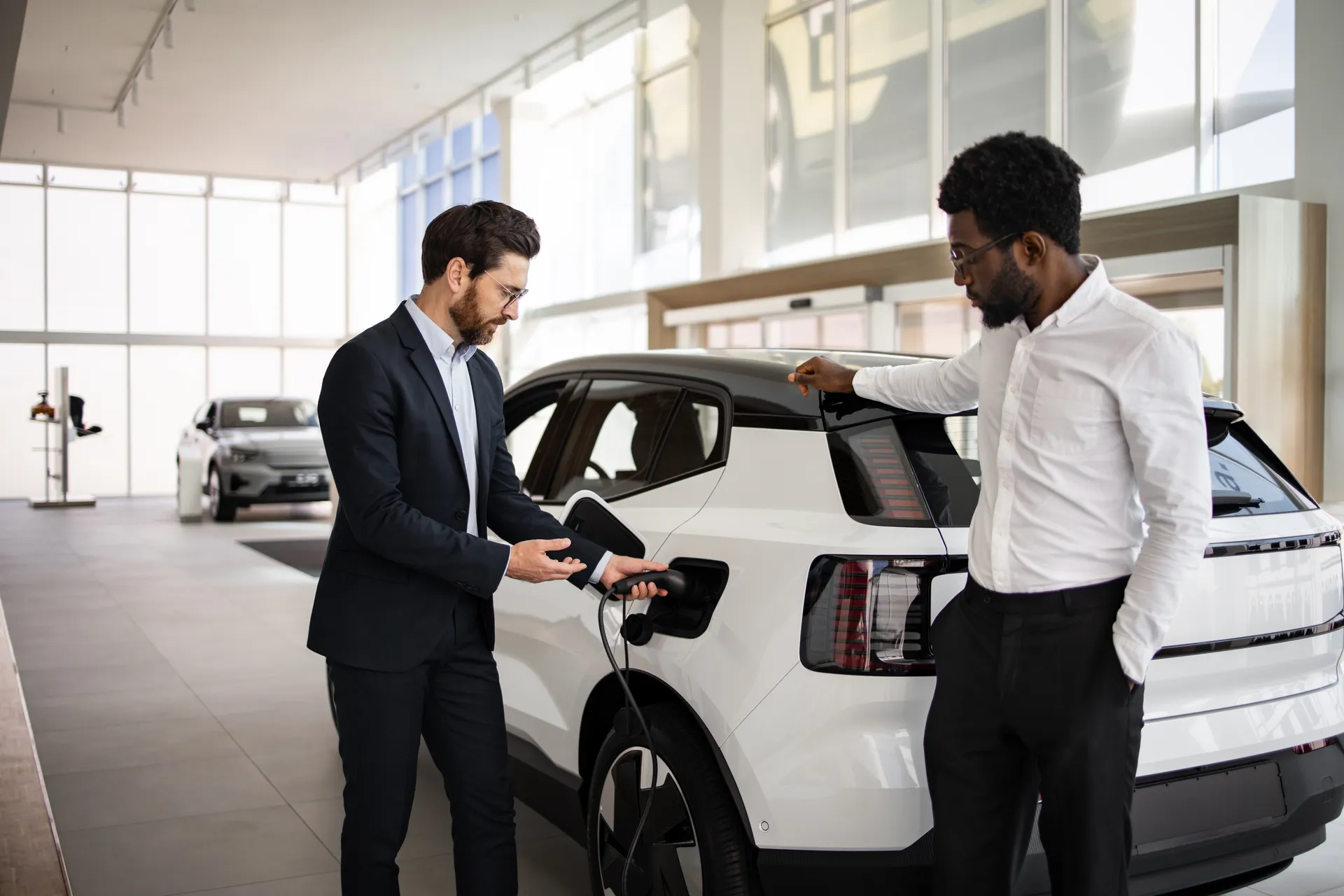 EV showroom, salesman demonstrates charging an EV