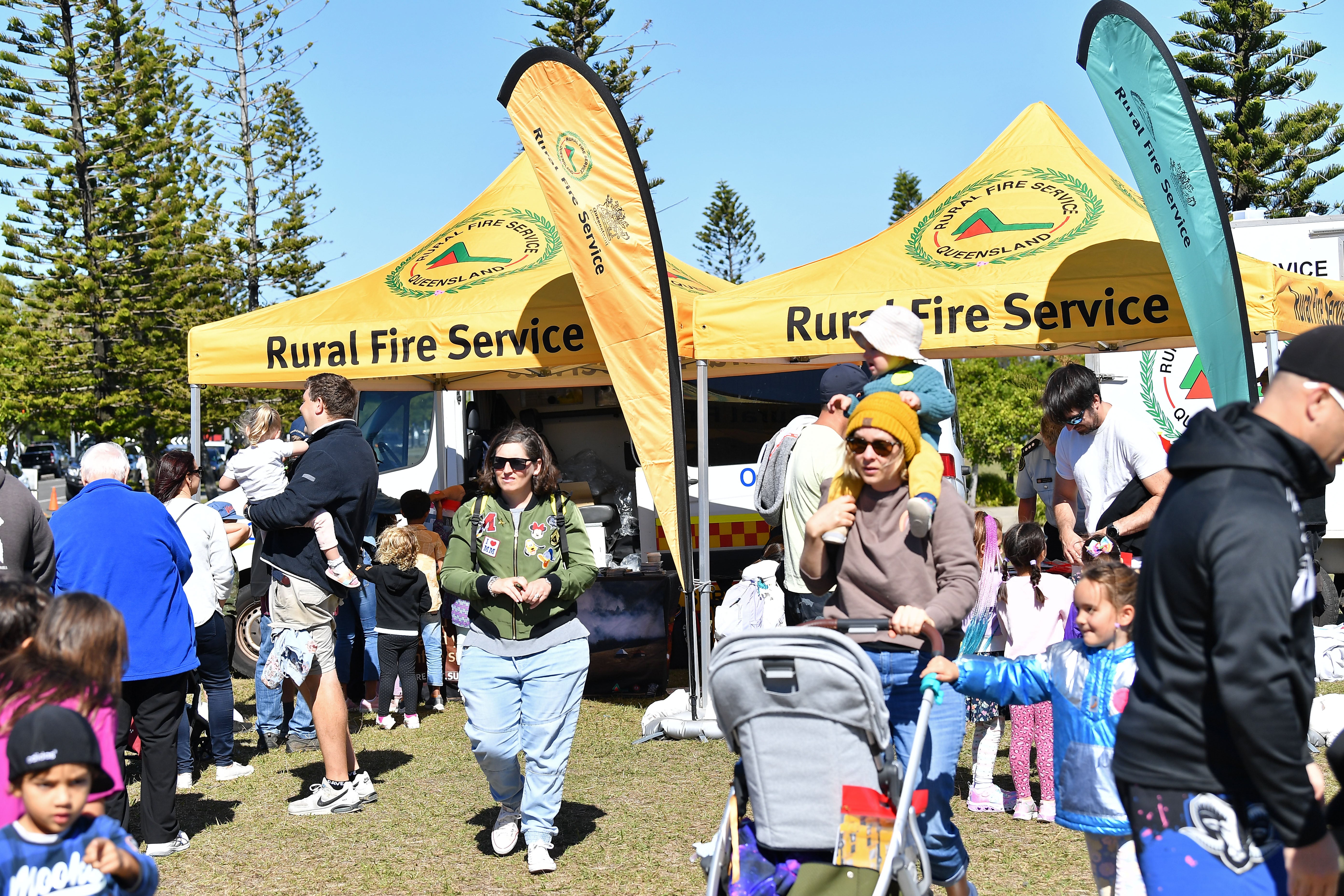 A larege group of young families mill around in front of a Rural Fire Brigade stall.