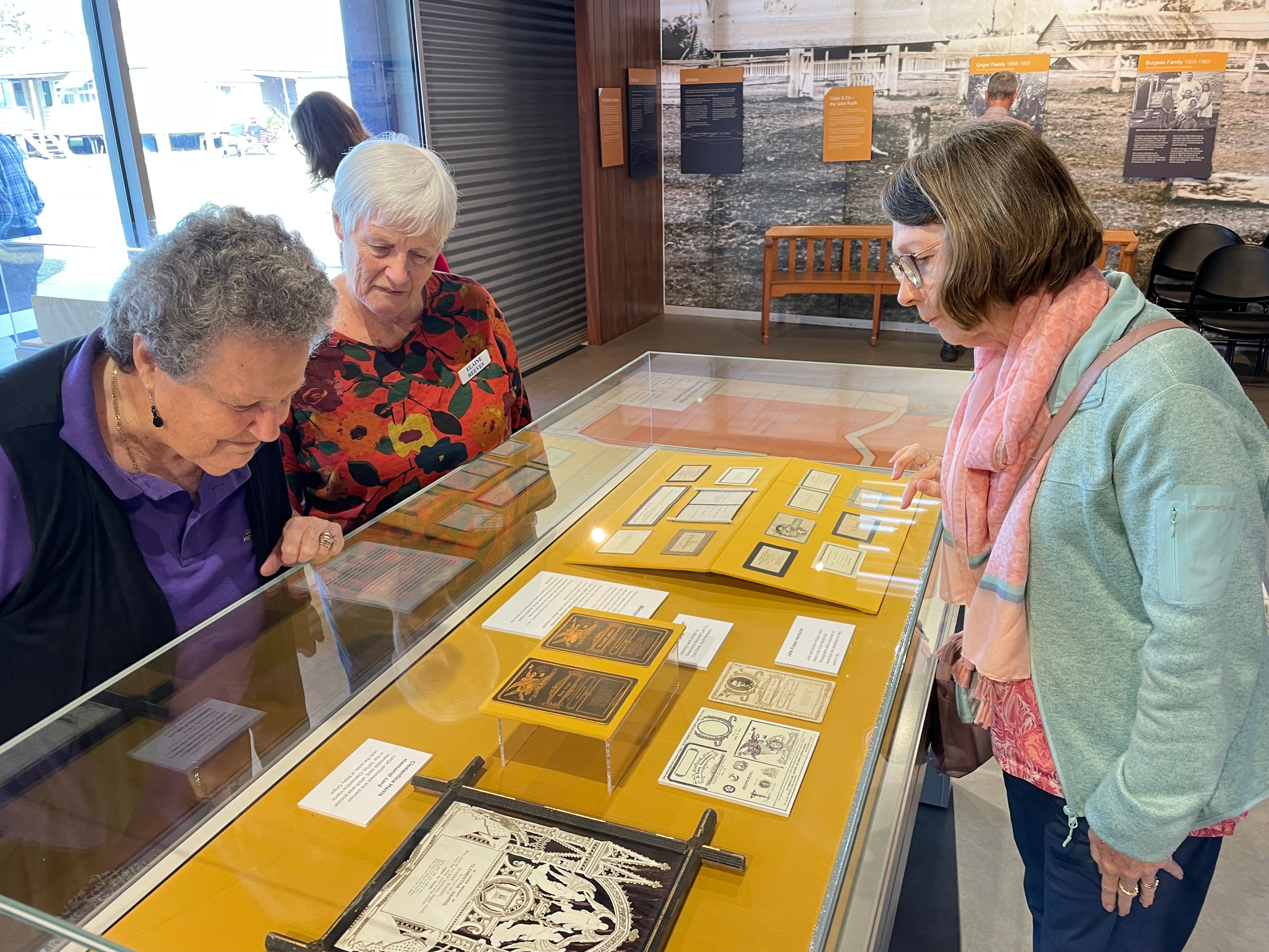 Bankfoot House exhibition - three ladies looking at items in the glass cases