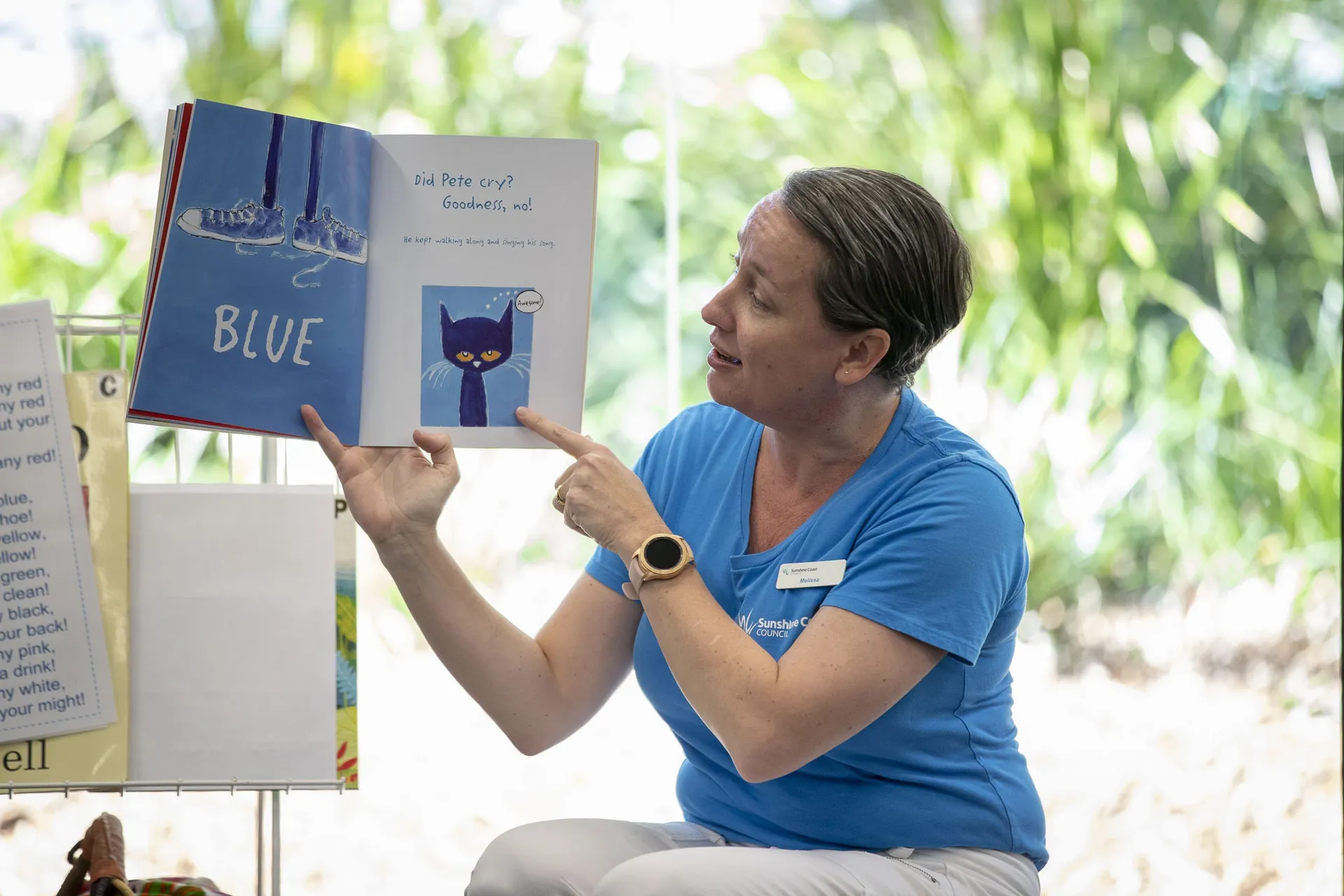 A Librarian holding up a book and pointing to an image in the book.