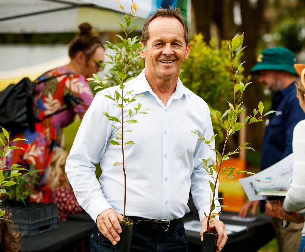 Cr Terry Landsberg holding two free trees to give away.