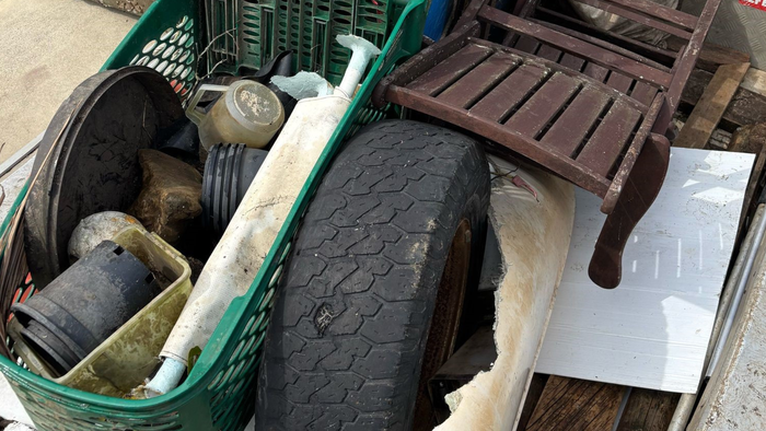 Rubbish collected, including a chair, tyre and plastic planting pots lay in a trailer. 