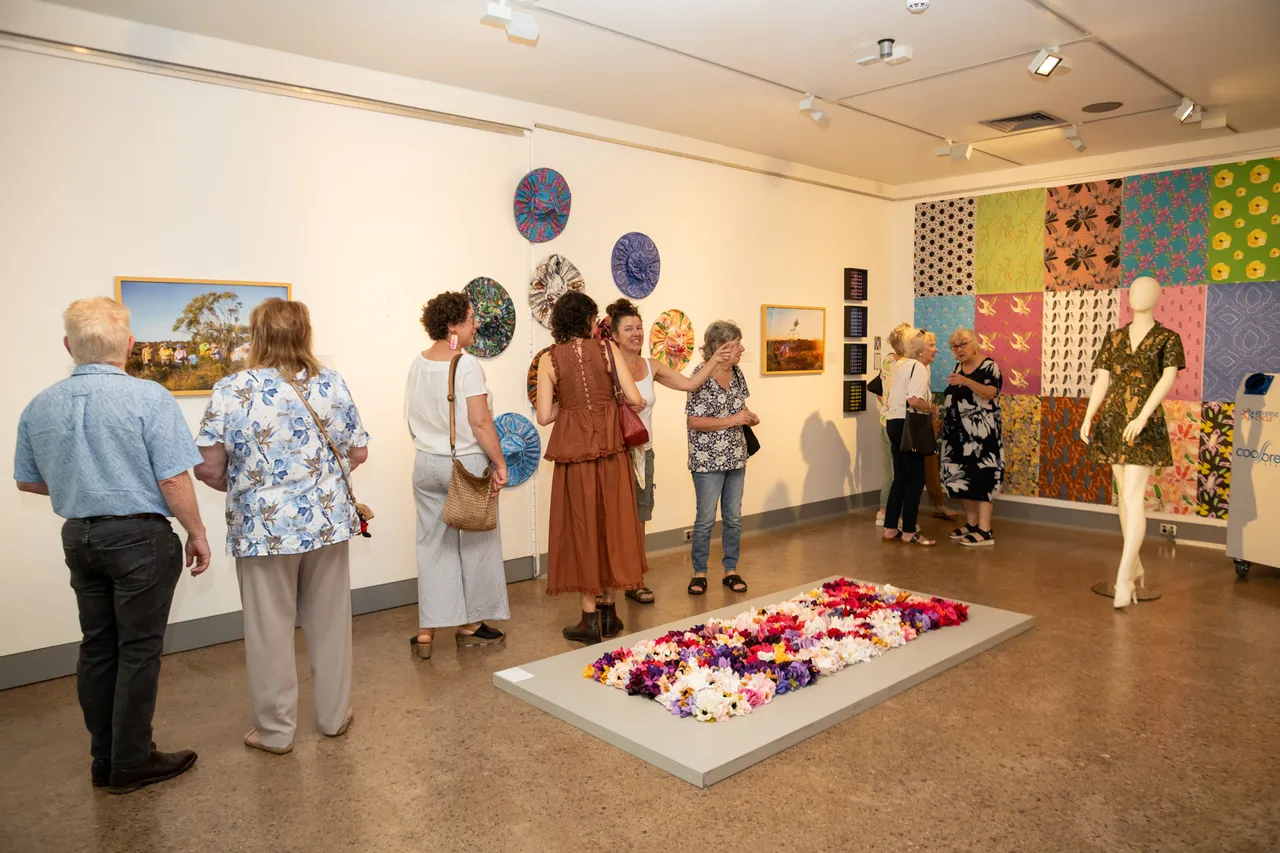 Crowds gather in the gallery surrounded by wildflower artworks