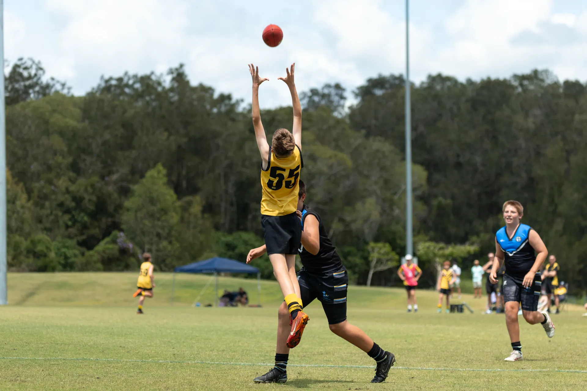 A young AFL player jumping for the ball.