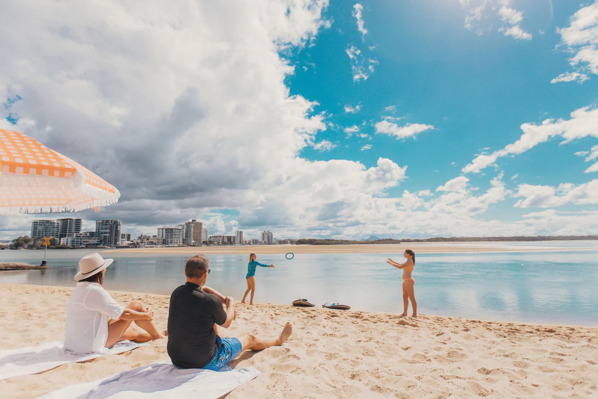 Couple sitting on Cotton Tree beach watching children play in the water