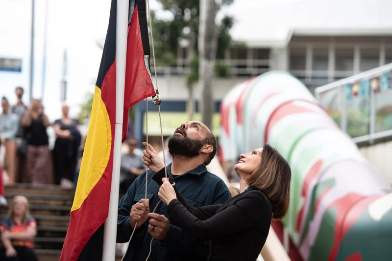 Kabi Kabi man Daniel Neill and Sunshine Coast Council Mayor Rosanna Natoli raise the Aboriginal flag at a NAIDOC Day ceremony in Nambour.  