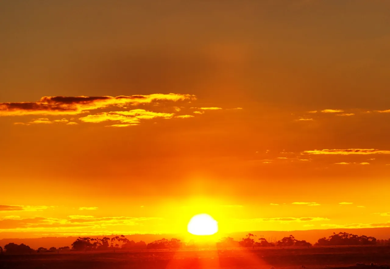 A blazing yellow sun sets on a red hot horizon.