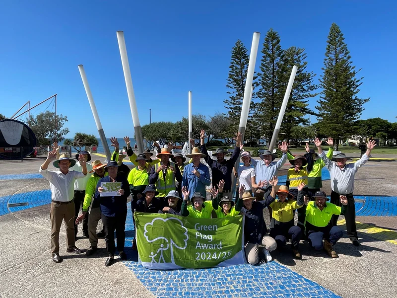 Kings Beach water park, group of people celebrating the Green Flag awards win. Blue skies and cobbled stone floor. 