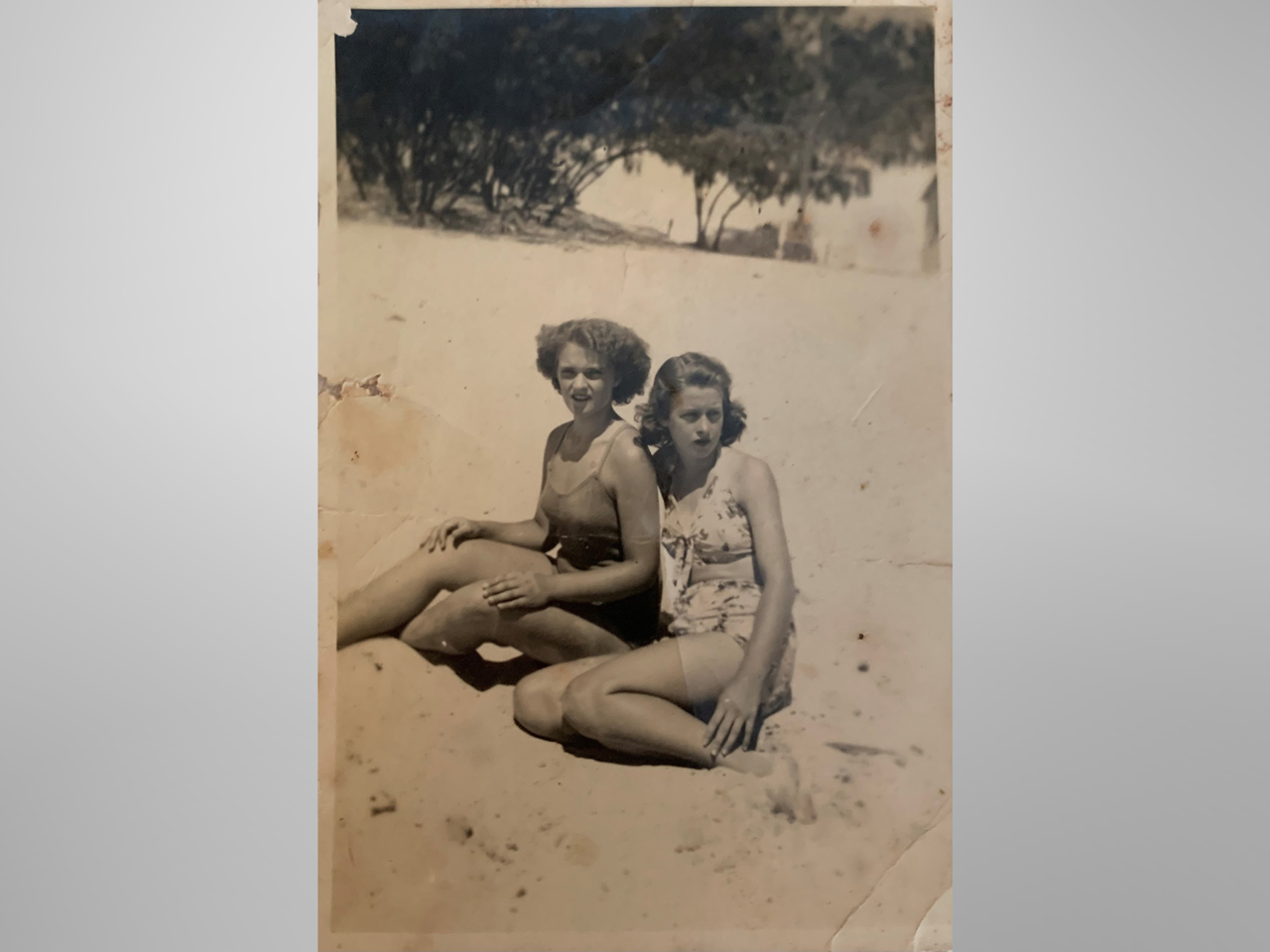 Sepia photo of two woman in swimwear at the beach in the 1940s.