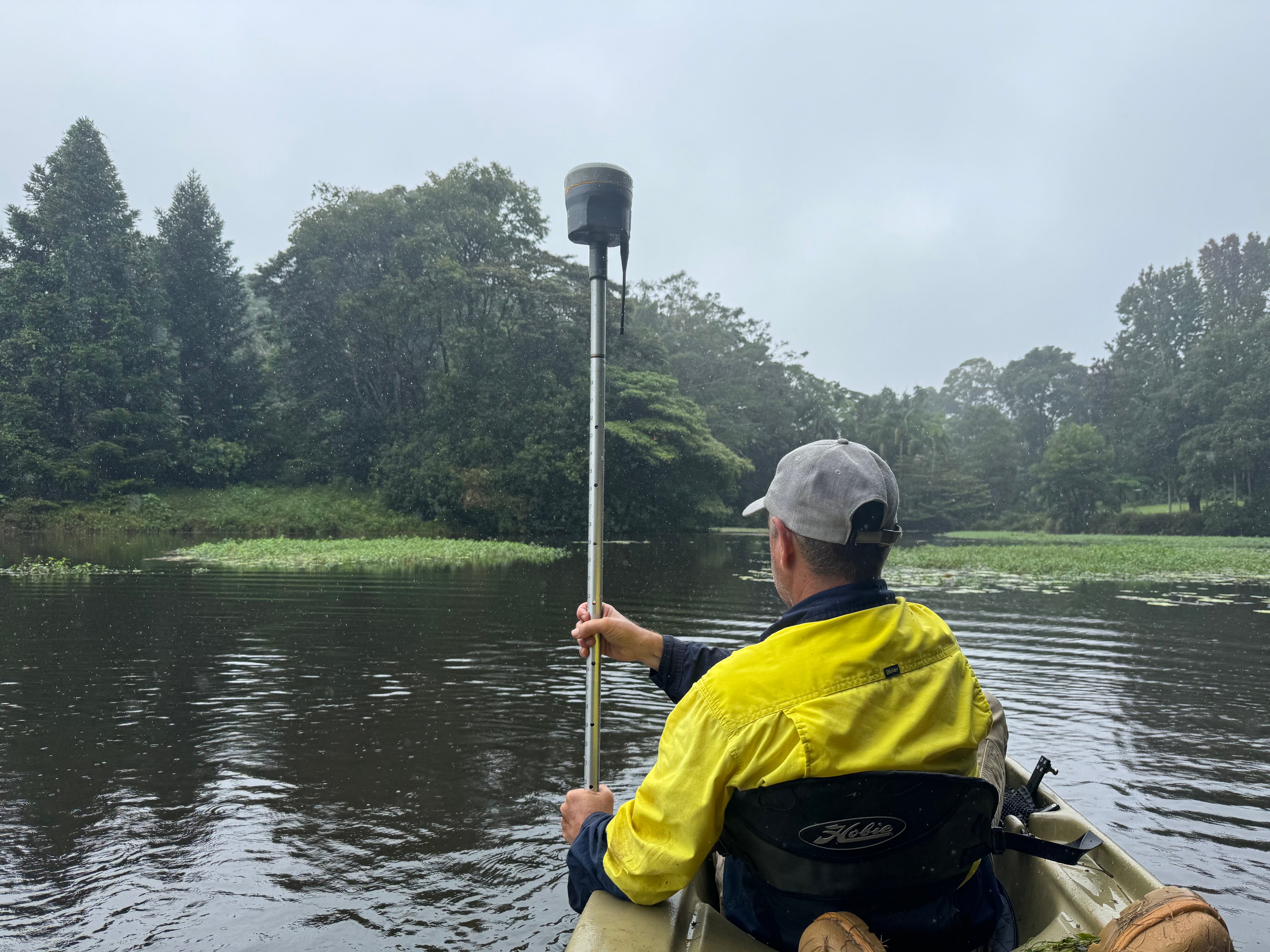 A surveyor takes measurements on a lake from a kayak.