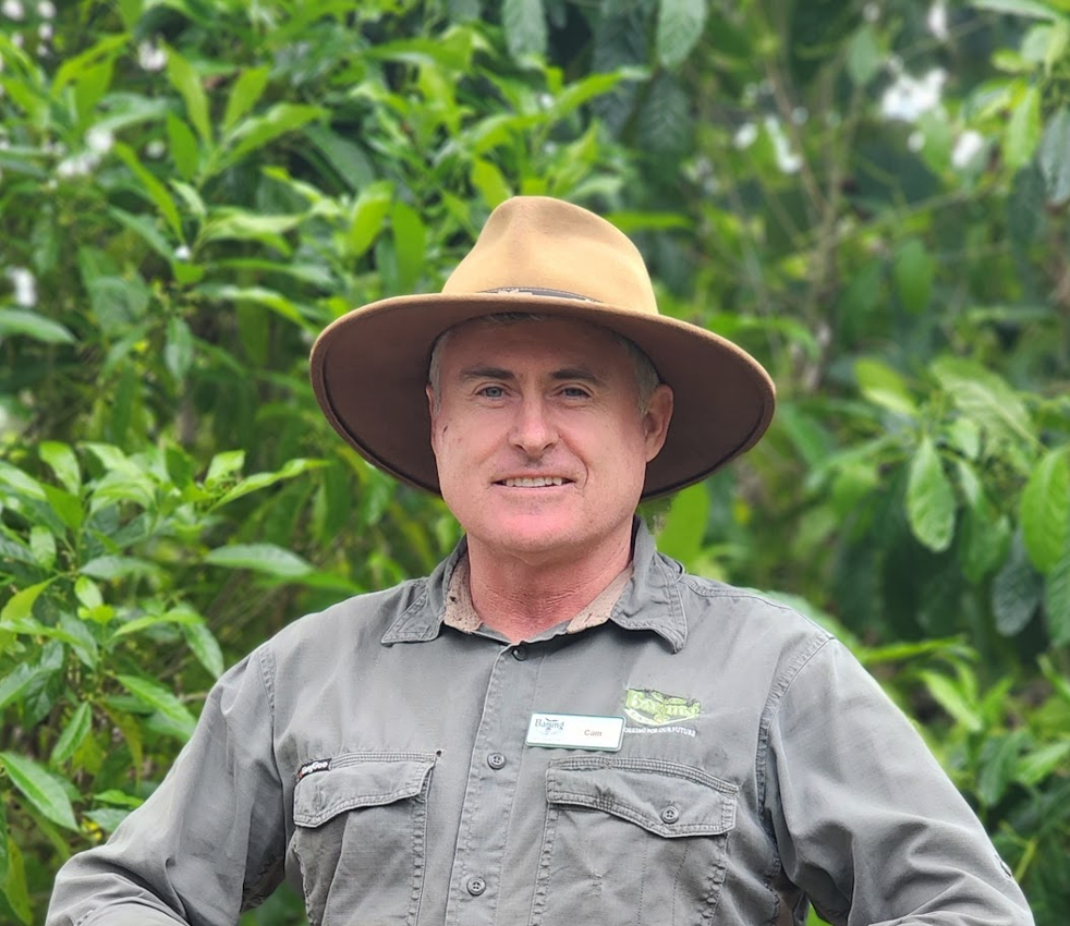 Cameron Burton stands in front of a greenery background.