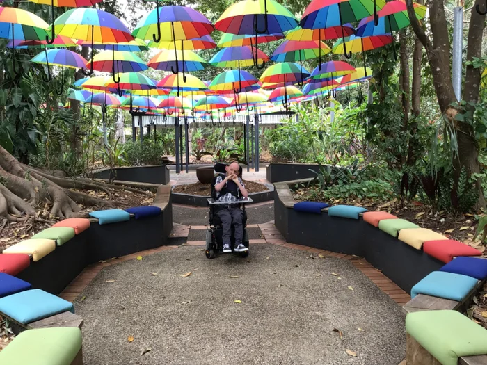 Person in wheelchair under umbrella installation at the Ginger Factory
