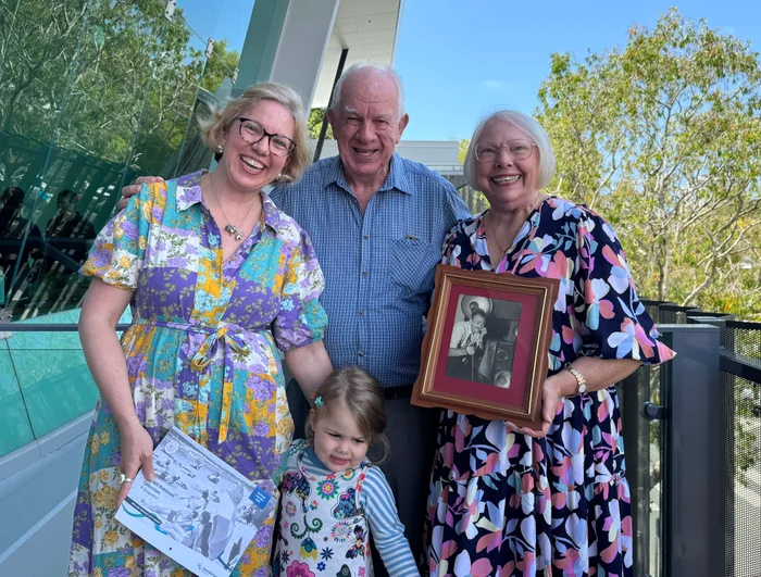 Bill Robinson's daughter and her husband, granddaughter and great granddaughter holding a photo of Bill and also a calendar