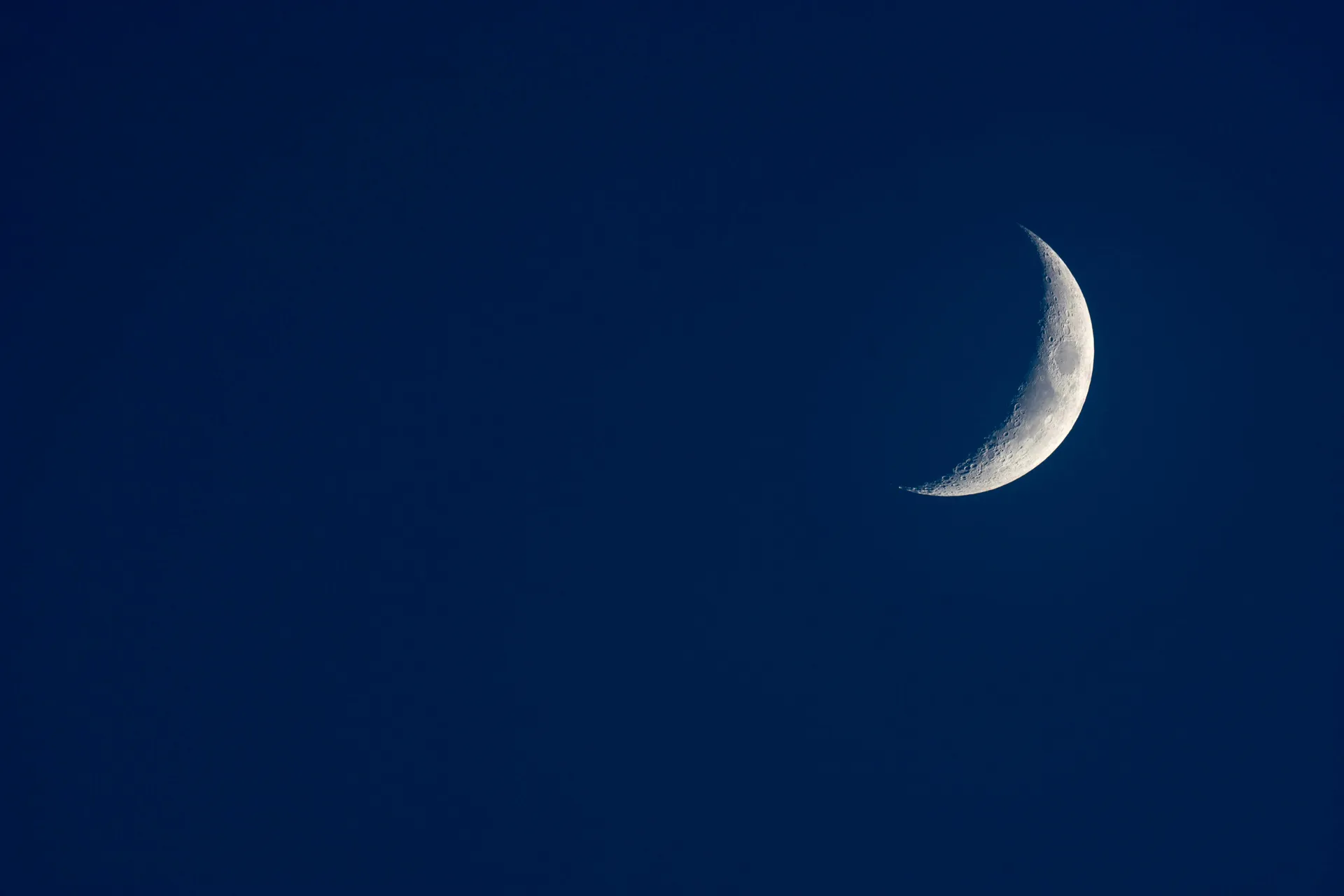 A new moon in a dark starless sky