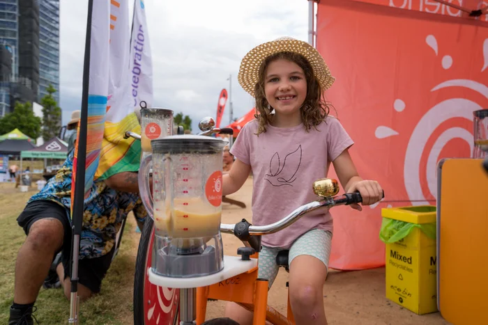 A girl rides on the smoothie bike, which uses pedal power to blend a smoothie.