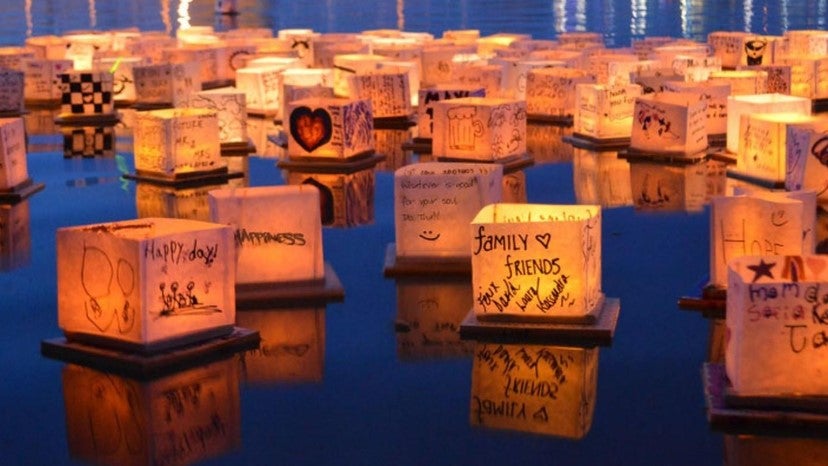Lanterns with writing on them floating on the water.