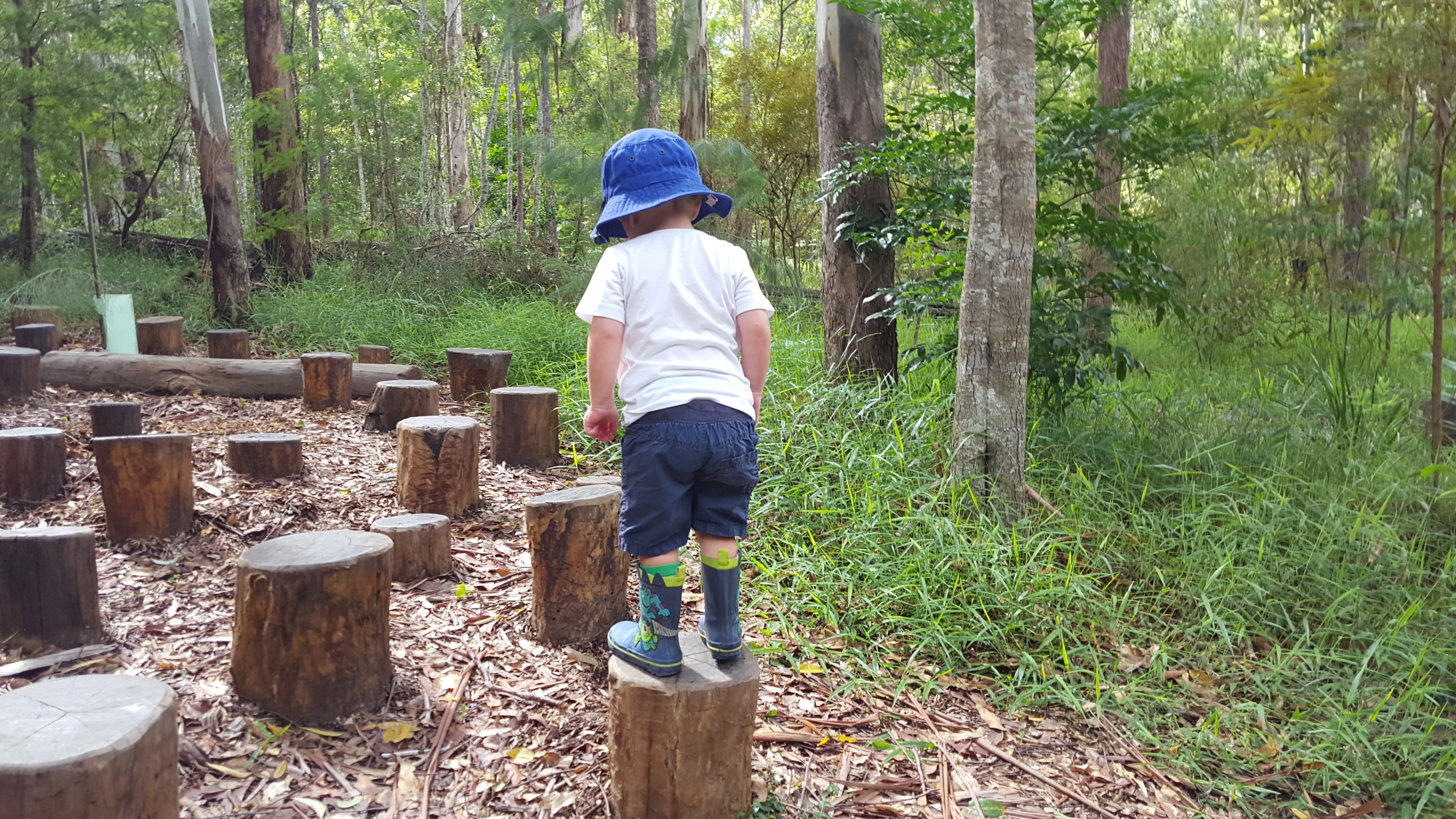young boy enjoying the log jump nature play elements
