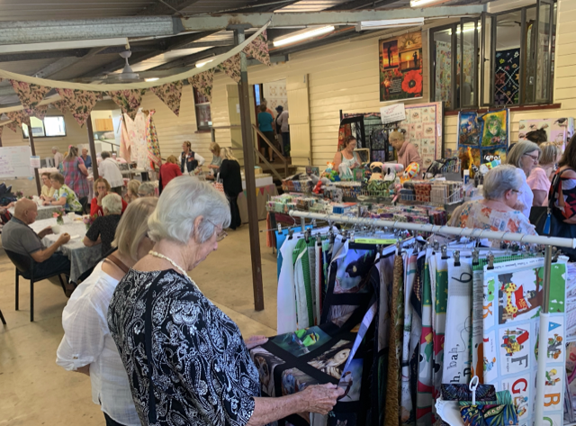 Ladies admiring cloth materials and colourful prints in a room with artwork. 