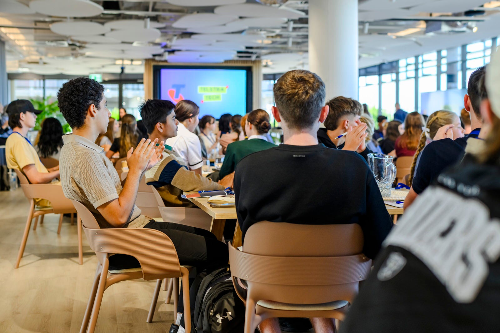 Students seated at a workshop, with a screen in the distance.