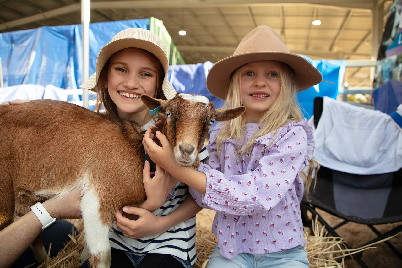A person and young child holding a goat