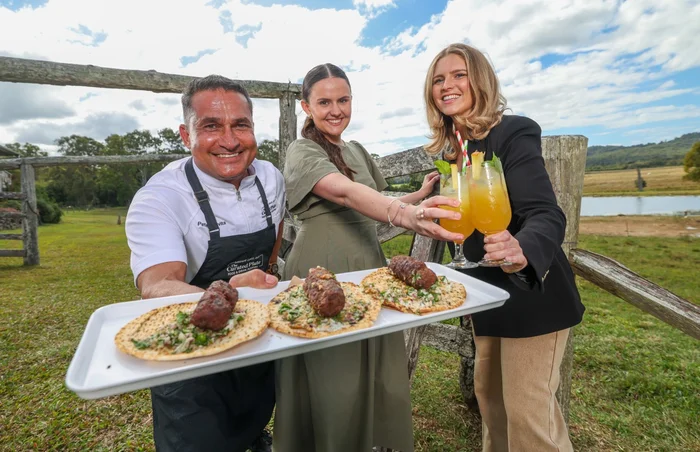 Three people holding out a tray of food and drinks.