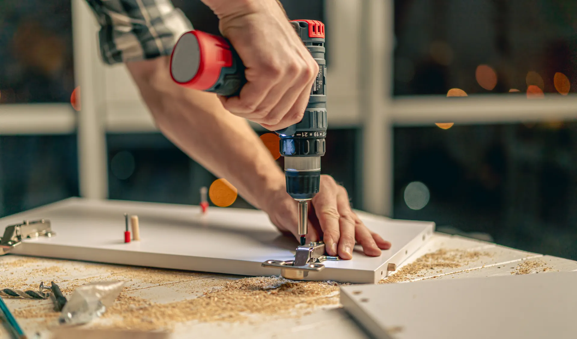 man attaching hinges to a cupboard door