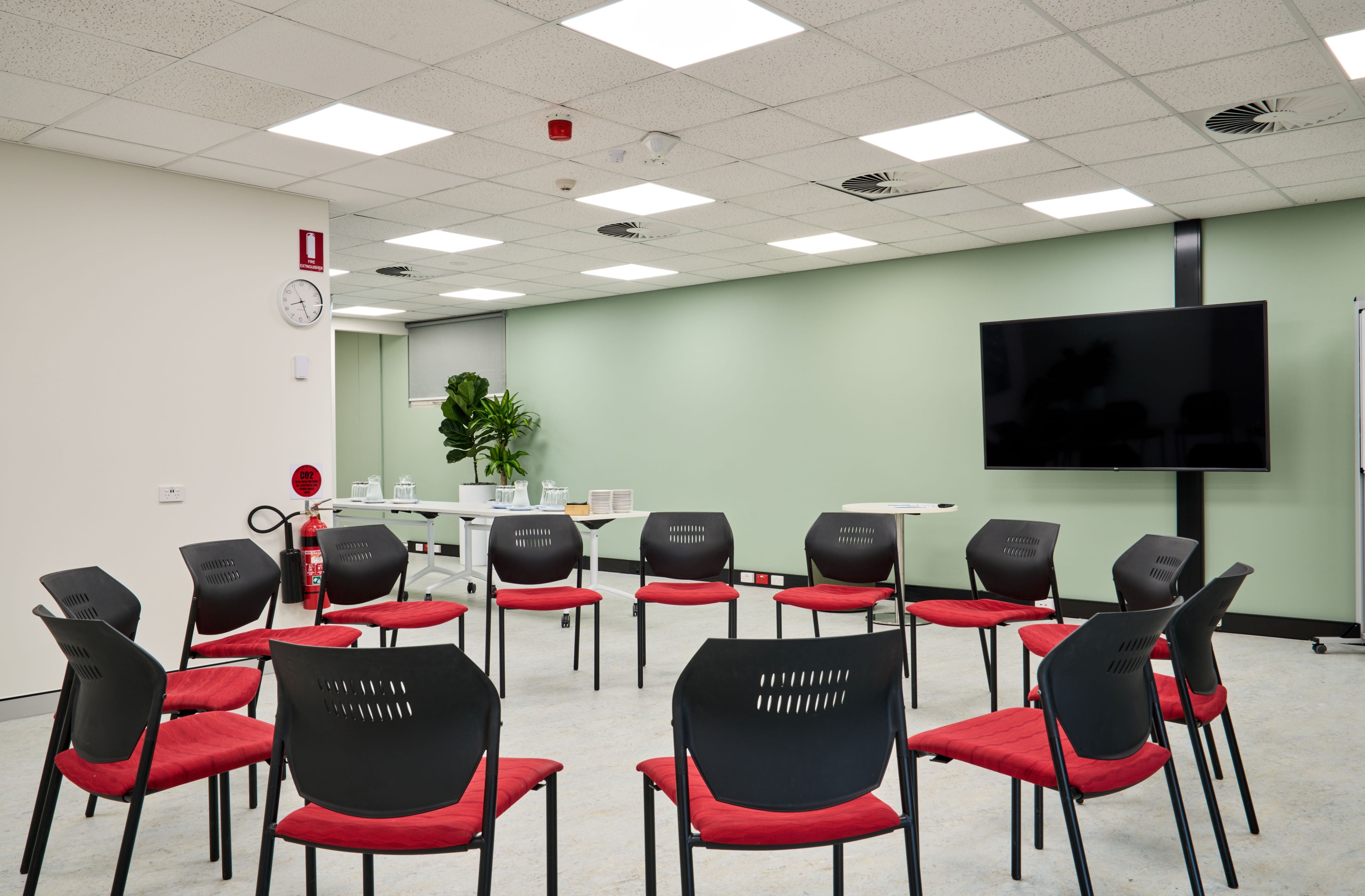 Indoor community meeting room with TV screen and chairs in a circle