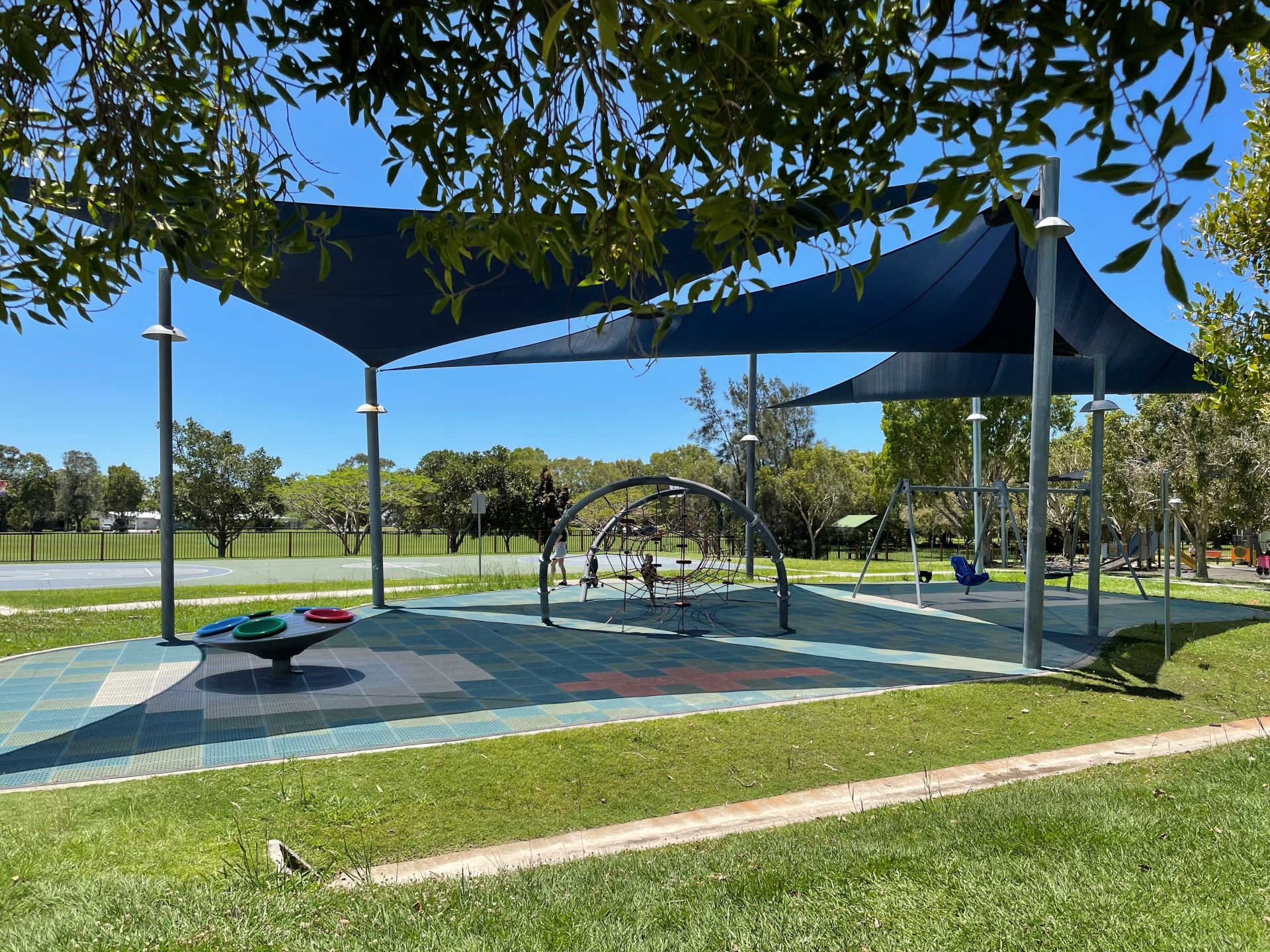 Al abilities playground with shade structures. Includes basket swing and climbing net