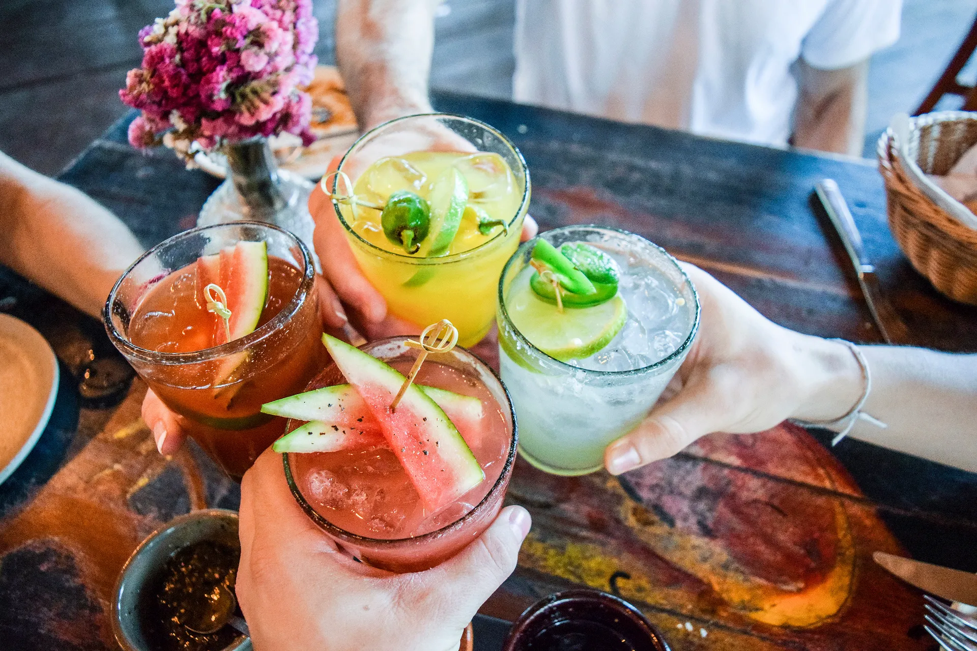 Four exotic looking drinks clinked together for cheers