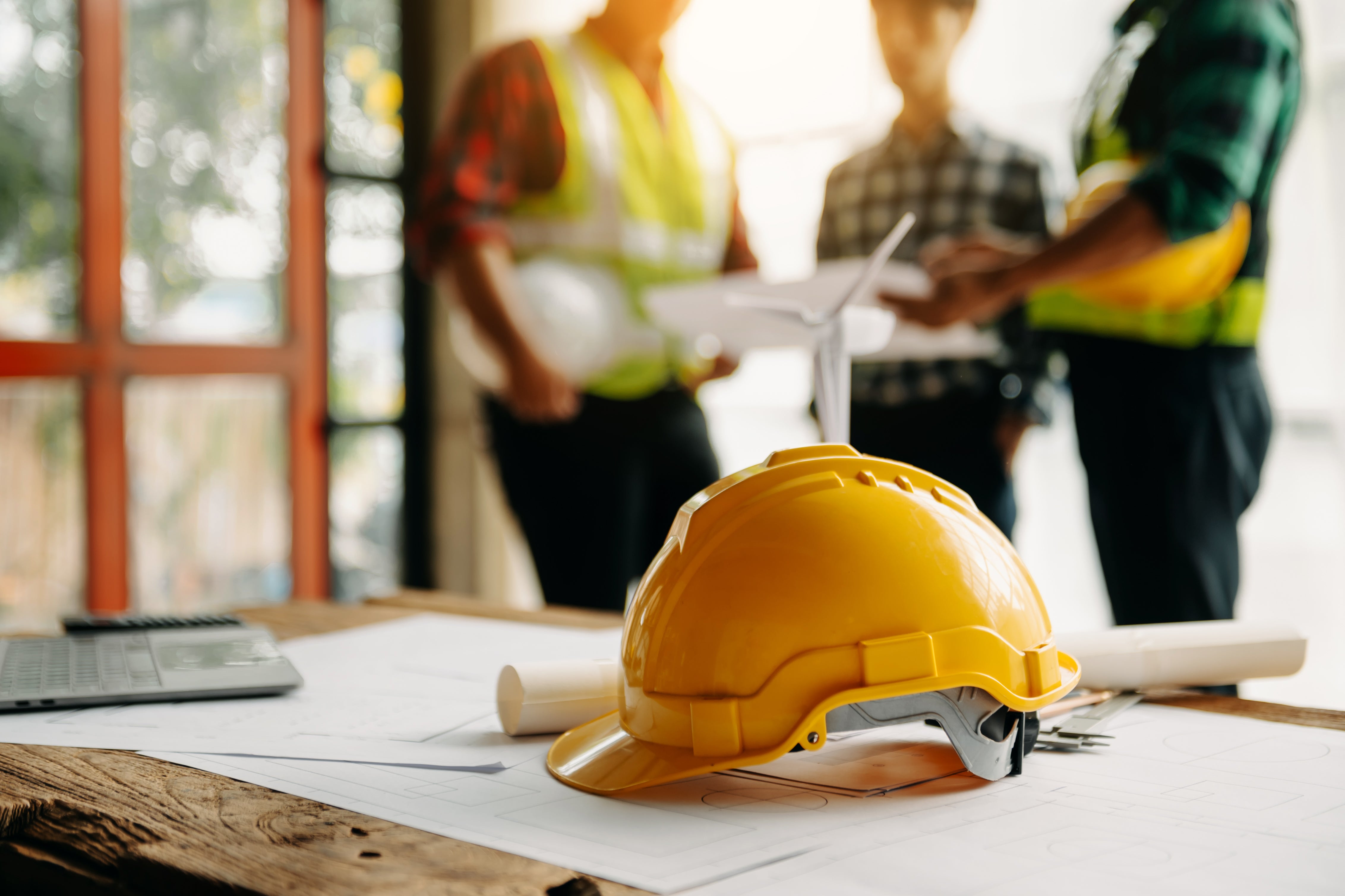 hard hat on a table with construction workers in the background