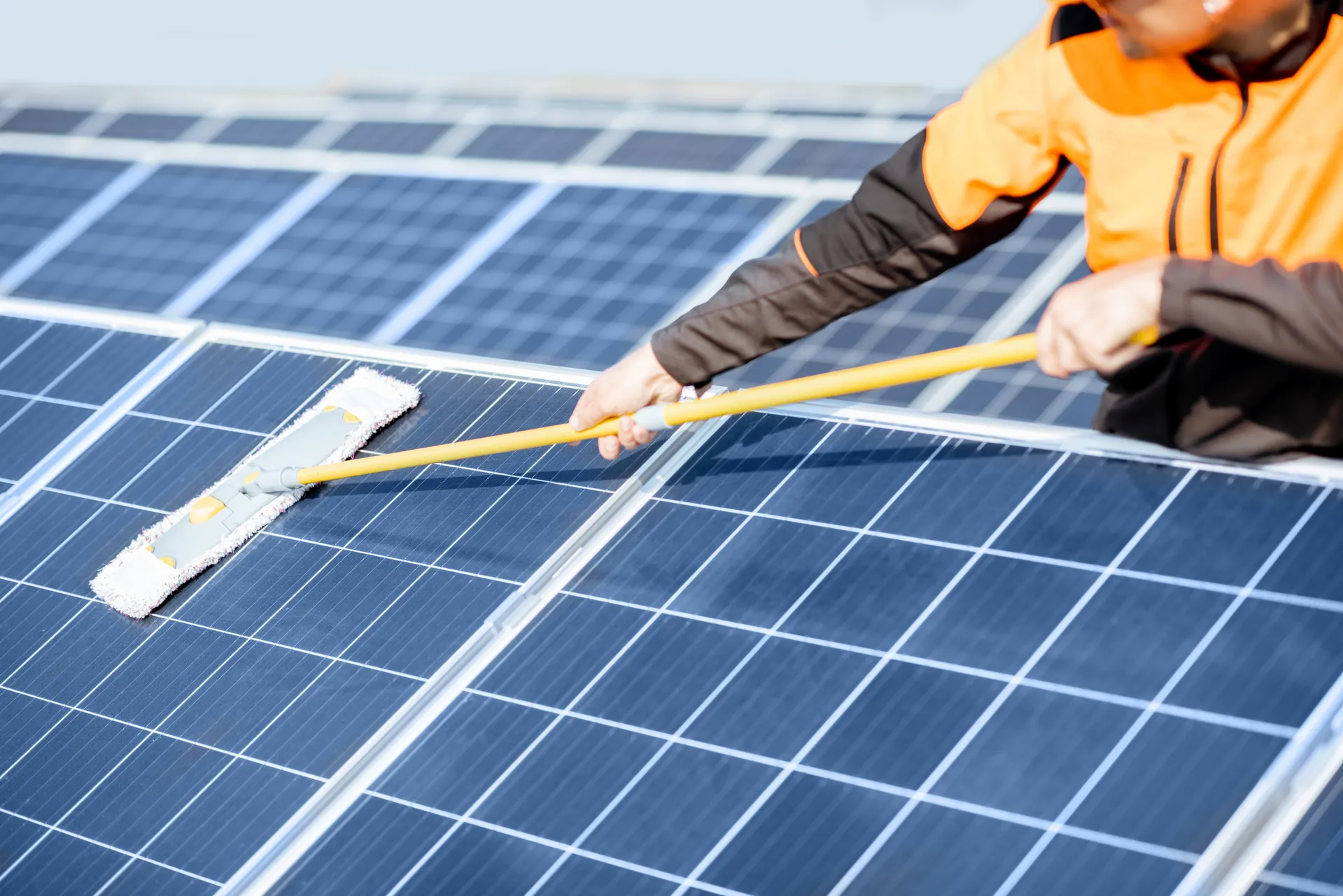 someone cleaning a solar array with a soft broom