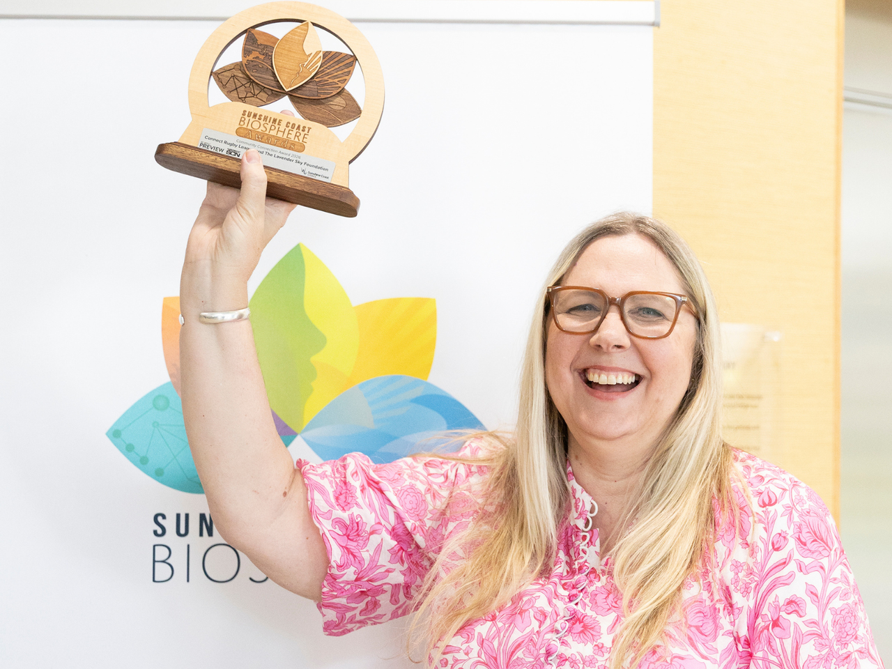 A woman holds up a trophy.