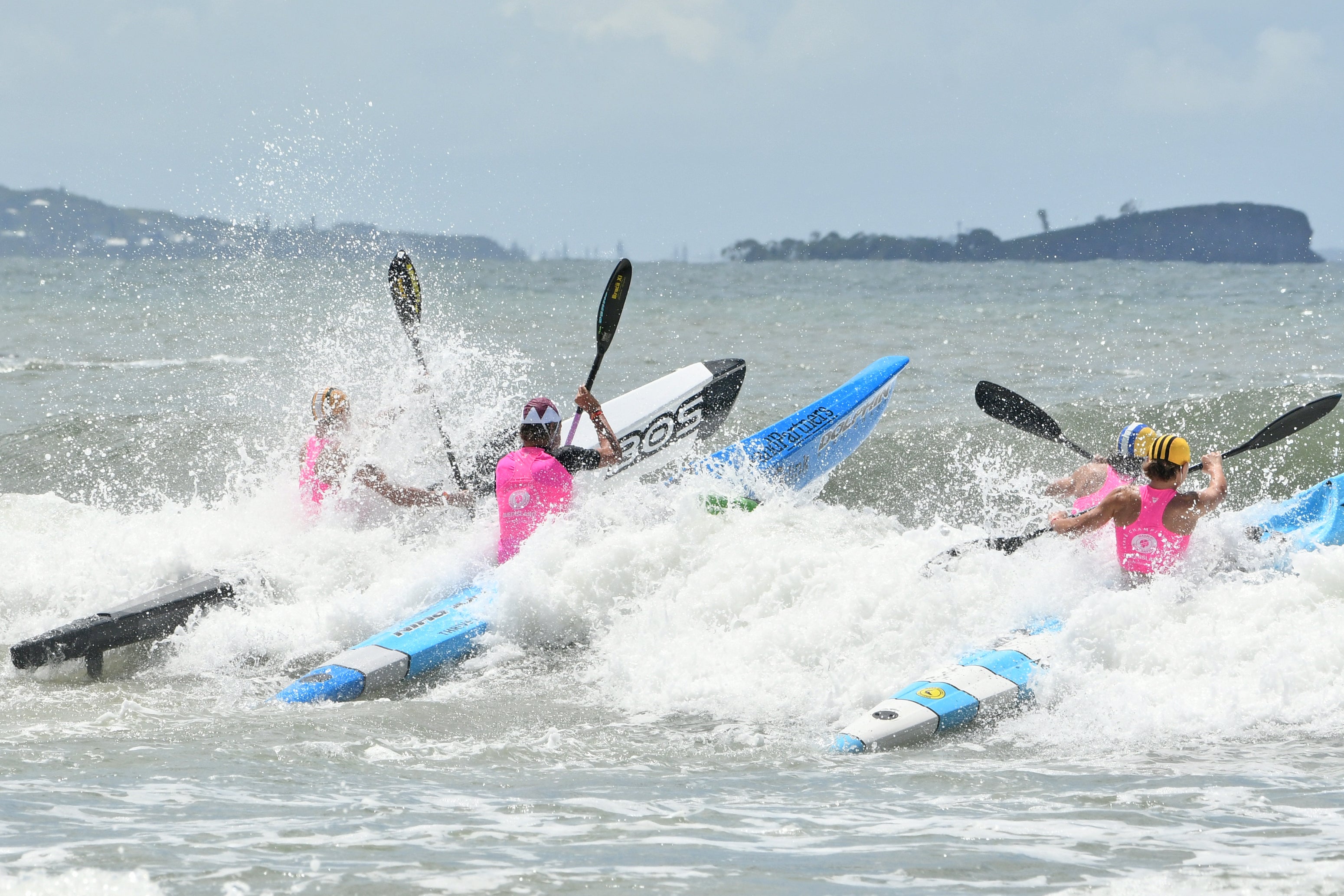 Three surf life savers navigating through some white water. Mudjimba Island in the background.