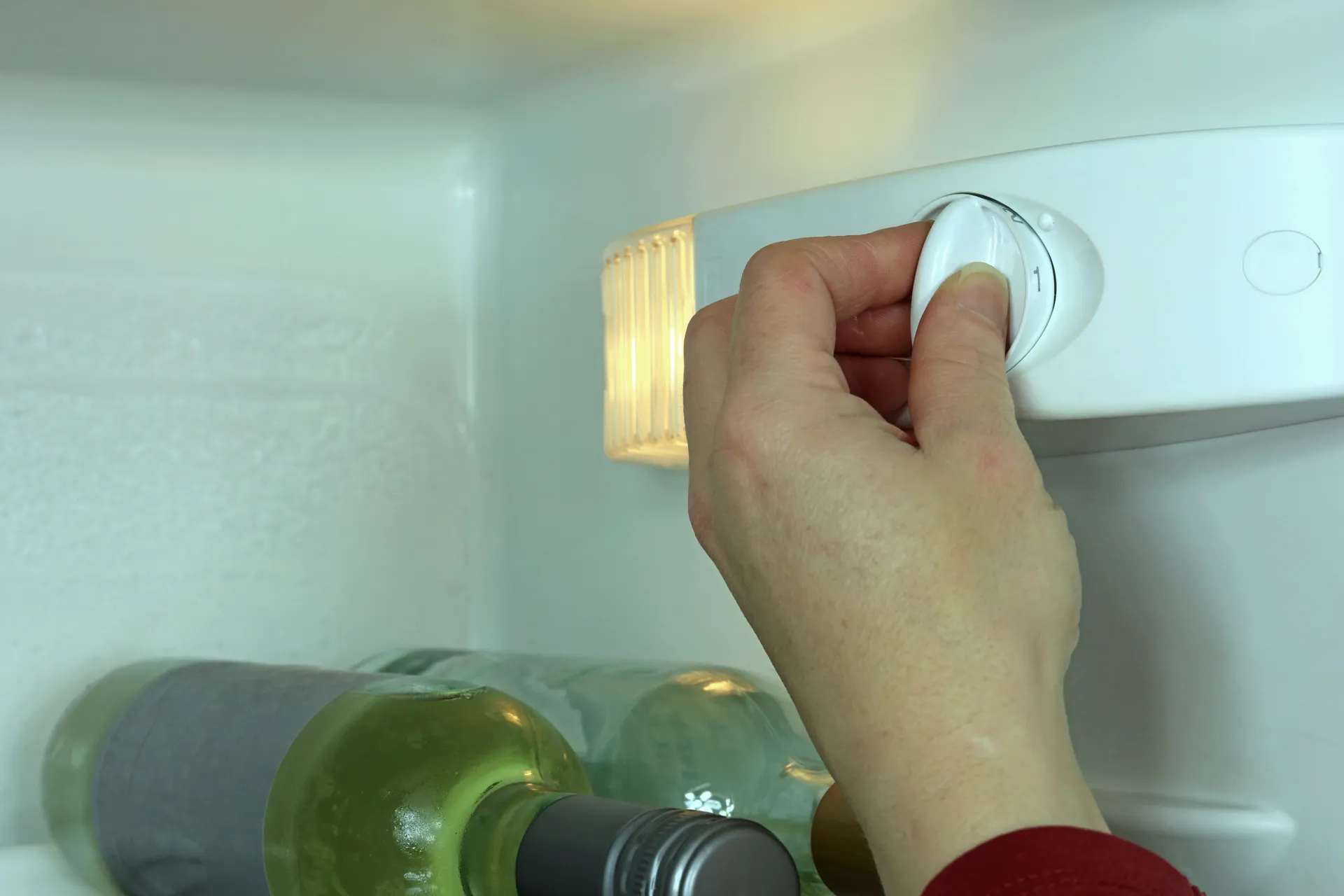 A hand adjusting the fridge dial